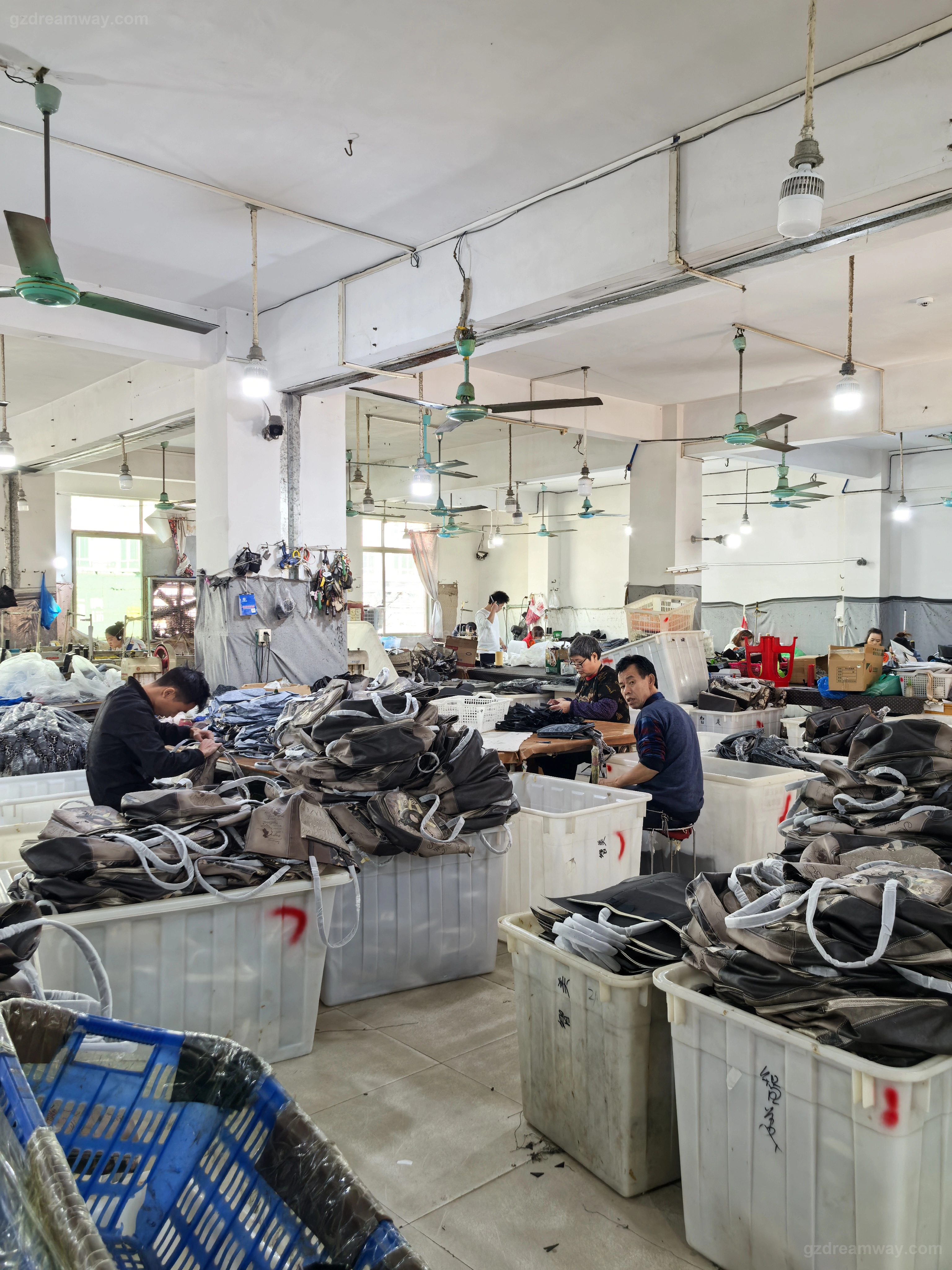 Panoramic view of GZ Dreamway handbag factory daily production floor in Guangzhou — leather tote bag panels, canvas bags and custom backpacks moving through assembly workstations