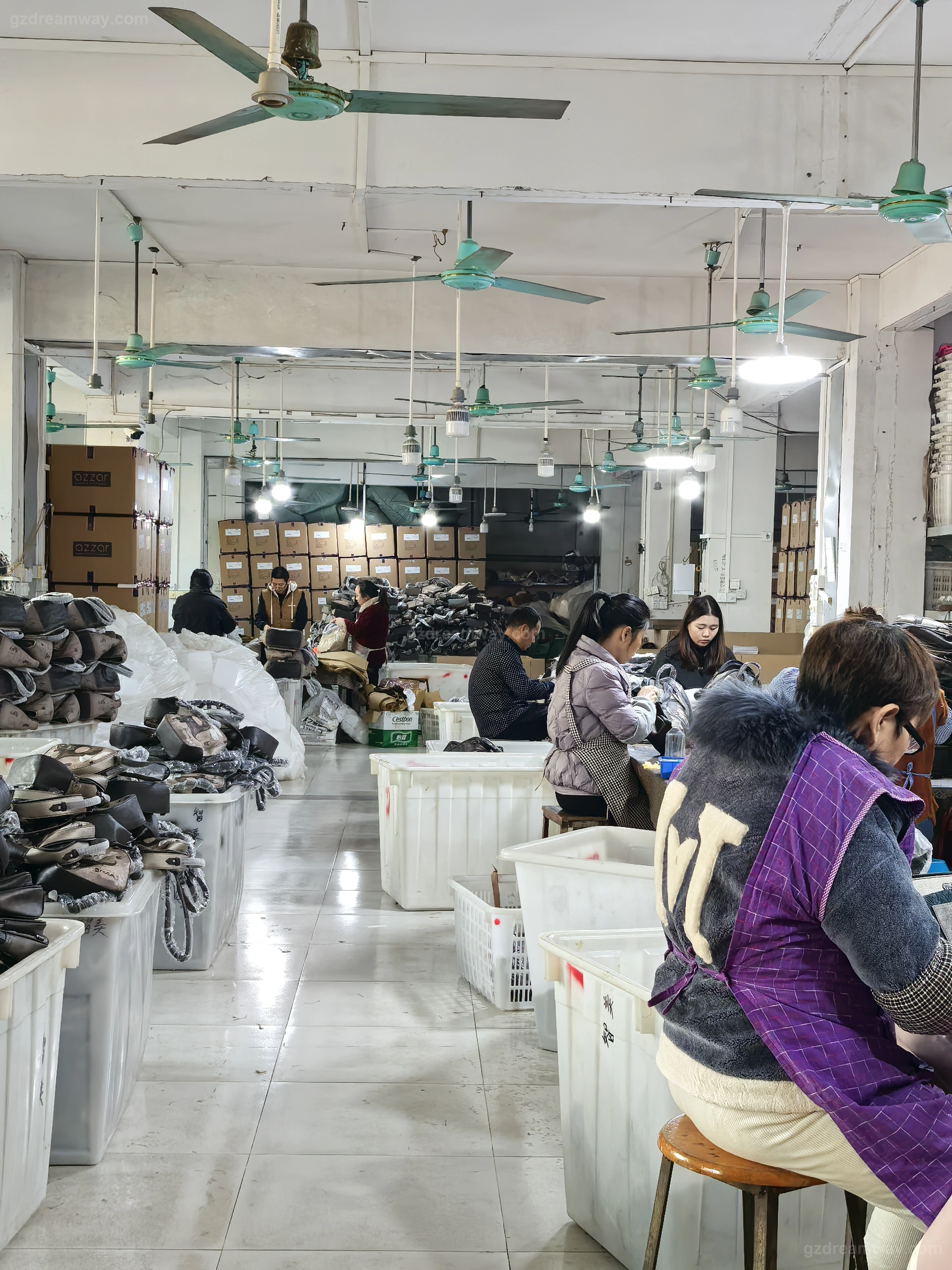 Final quality control and packaging station inside a handbag factory with workers inspecting finished custom leather tote bags, backpacks and wallets and packing them into 5-ply export cartons