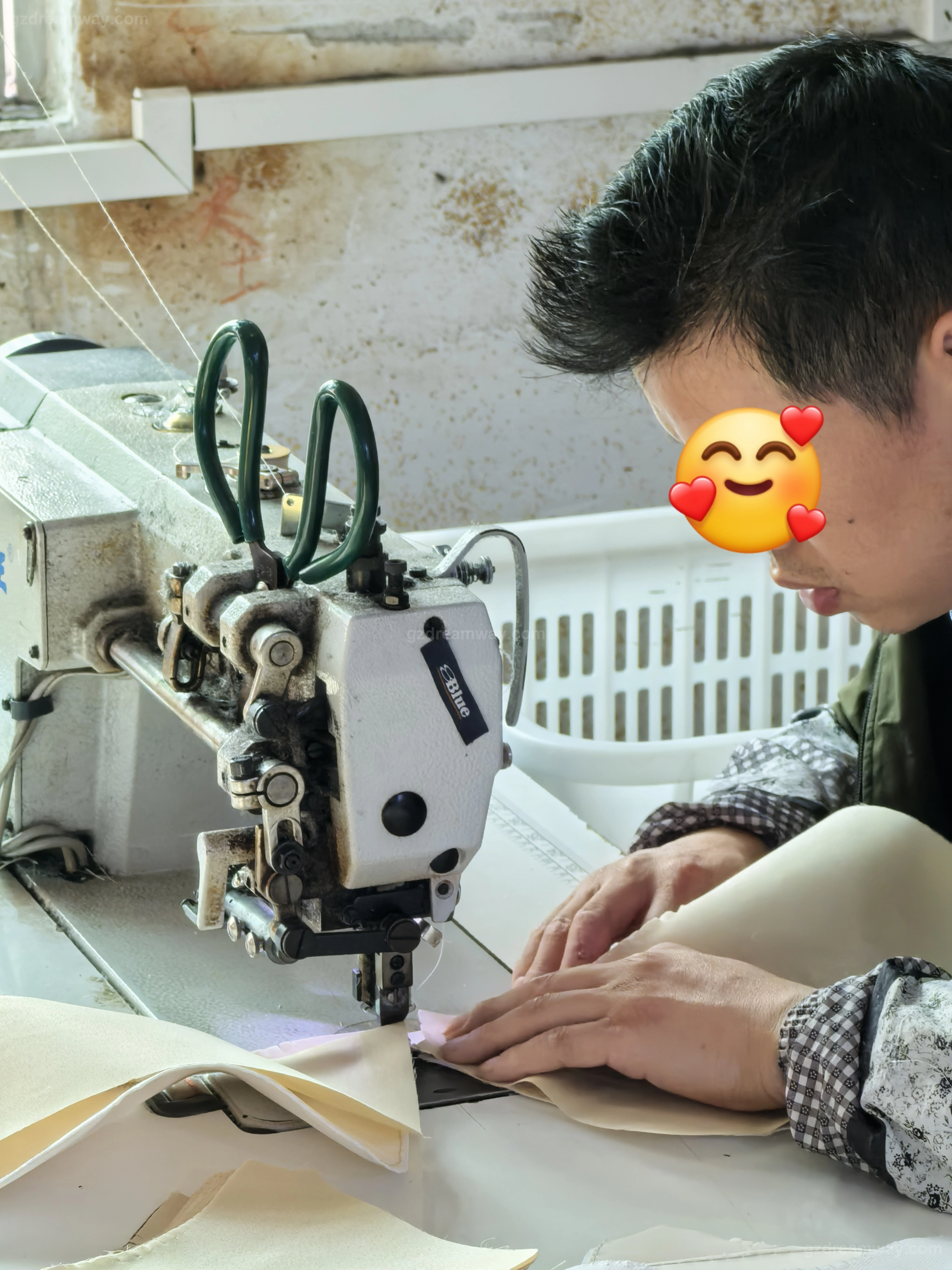 Skilled sewer working on a cylinder-bed sewing machine to attach edge binding and lining to a light colored custom leather handbag tote with logo at GZ Dreamway Guangzhou workshop
