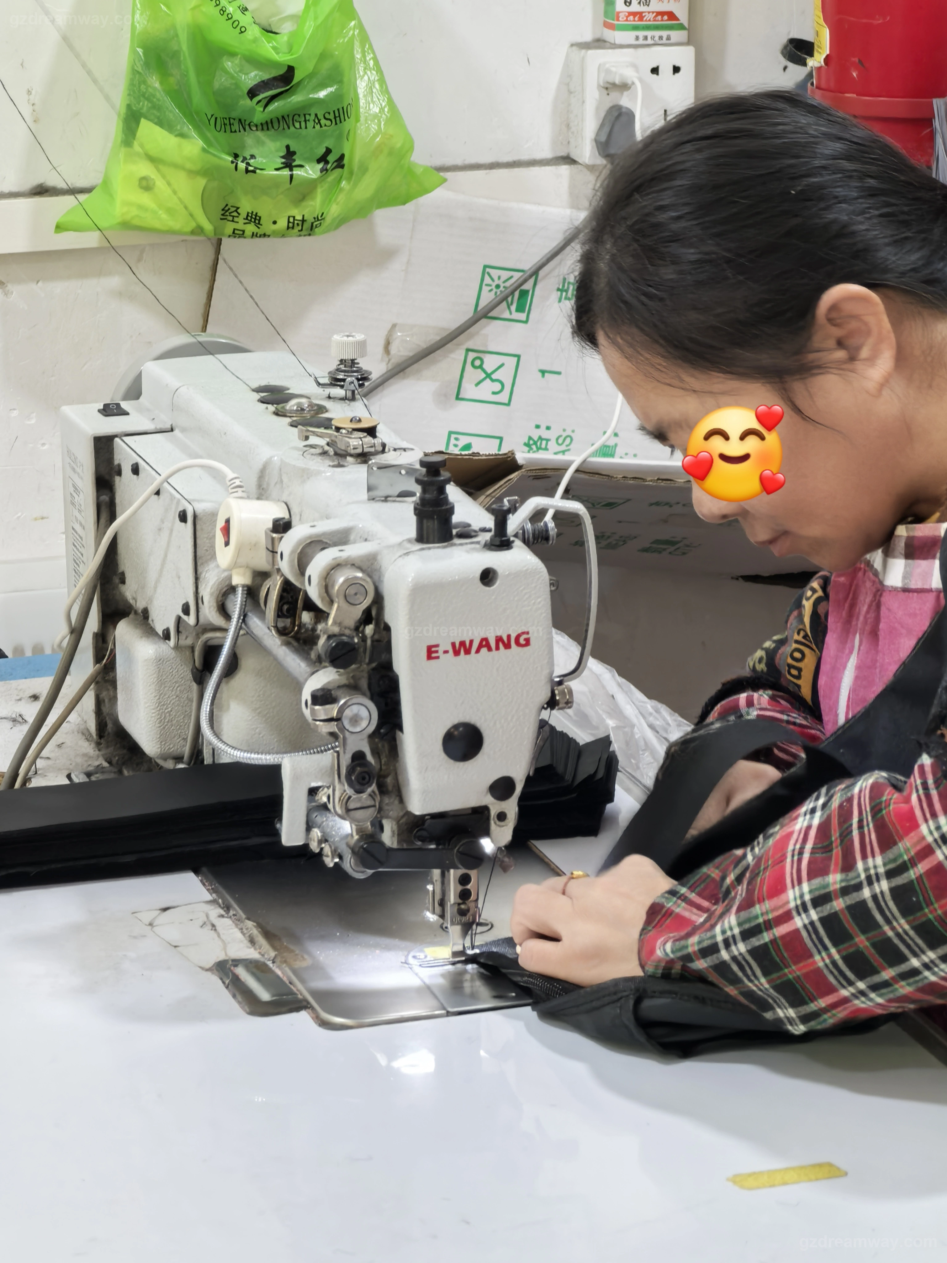 Industrial heavy-duty E-WANG sewing machine with LED work light doing precise edge stitching on black leather handbag straps, tote bag webbing and custom backpack binding at GZ Dreamway production line